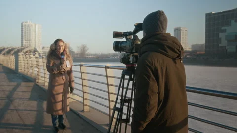 Journalist and Operator Filming News Report on Bridge for TV Channel Stock Footage 300404669