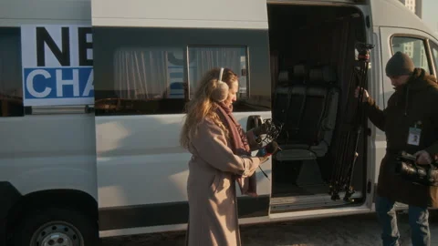Journalist and Operator Walking out of TV Production Van to Film News Report Stock Footage 300403494