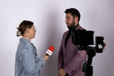 A journalist is interviewing a man on camera with a microphone Stock Photos