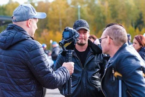 Journalist man filming interview with another man using camera on a gimbal Stock Photos