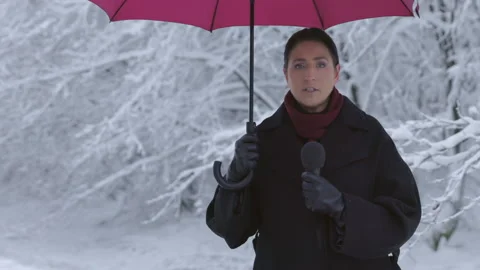 A journalist is reporting on the current weather situation in a live broadcast Vídeos de archivo 214045291