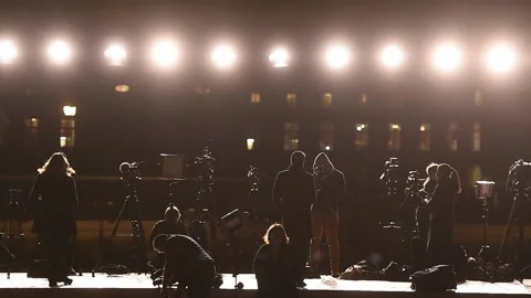 Journalists making a live broadcast on a large scene in front of spotlights 스톡 동영상 172020165