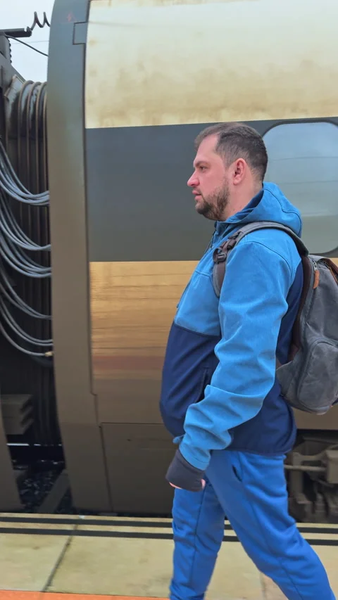 Journey in the Drizzle - Man with Backpack by the Train on a Rainy Day Stock Footage 263780268