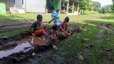 The joy of three small children playing with water and mud on a dirt road Stock Footage 309388114