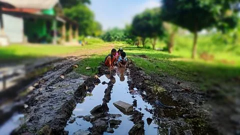 The joy of three small children playing with water and mud. Stock Photos