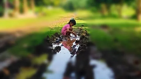 The joy of three small children playing with water and mud. Stock Photos