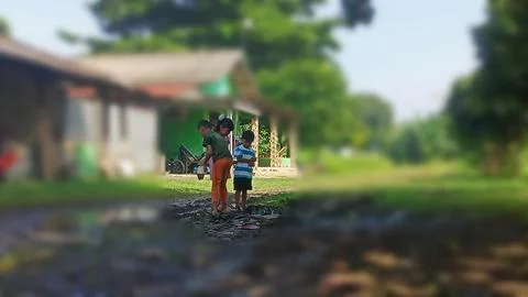 The joy of three small children playing with water and mud. Stock Photos