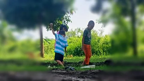 The joy of three small children playing with water and mud. Stock Photos
