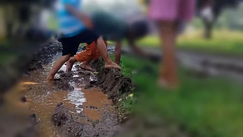 The joy of three small children playing with water and mud. Stock Photos