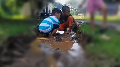 The joy of three small children playing with water and mud. Stock Photos