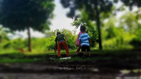 The joy of three small children playing with water and mud. Stock Photos