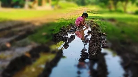 The joy of three small children playing with water and mud. Stock Photos