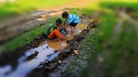 The joy of three small children playing with water and mud. Stock Photos