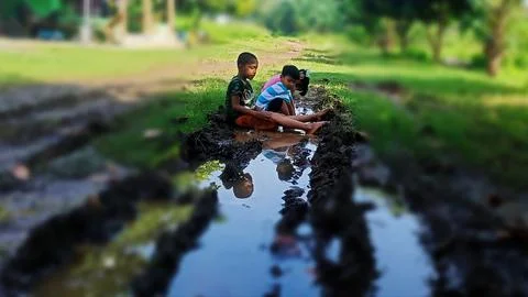 The joy of three small children playing with water and mud. Stock Photos