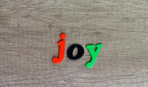 Joy    word  written with  plastic  multi colored  letters on a wooden table Stock Photos