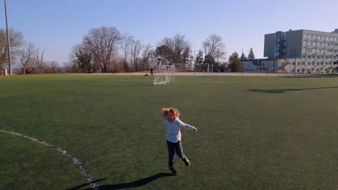 A joyful 7-year-old boy running across an empty stadium field on a sunny day Video stock 299364612