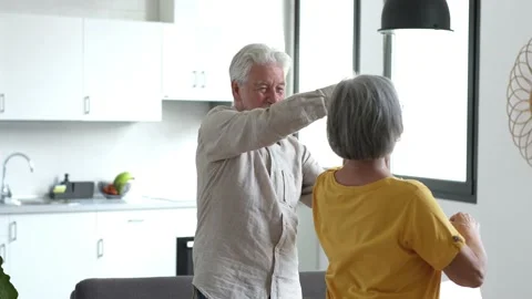 Joyful active old retired romantic couple dancing laughing in living room, happy Stock Footage 237939327
