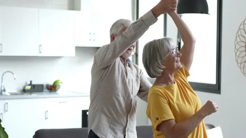 Joyful active old retired romantic couple dancing laughing in living room, happy Stock Footage 237939431