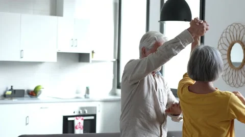 Joyful active old retired romantic couple dancing laughing in living room, happy Stock Footage 237939563