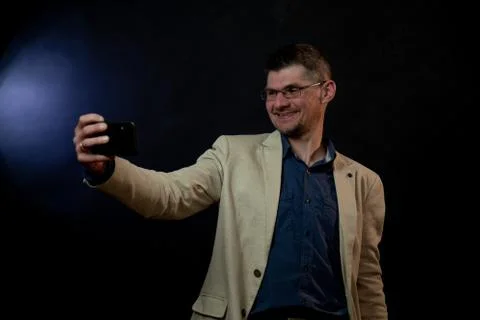 Joyful actor in beige jacket makes selfie pulling faces Stock Photos