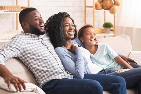 Joyful african american family watching comedy show on tv together Stock Photos