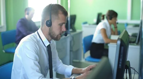 Joyful agent working in a call center with his headset Stock Footage 67666363