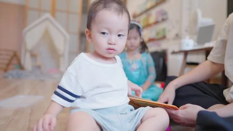 Joyful asian boy sitting inside the living room with his family during daycare Stock Footage 279505983
