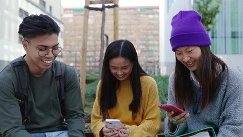 Joyful asian student friends using cell phone standing together in city street. Stock Footage 237028726