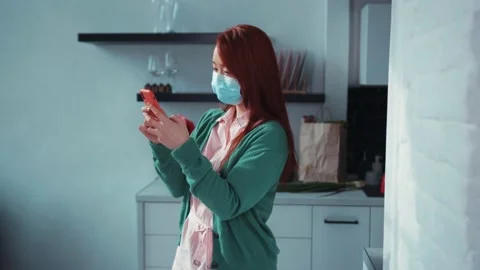 Joyful attractive red-haired Chinese woman taking off face mask smiling while Stock Footage 131666328