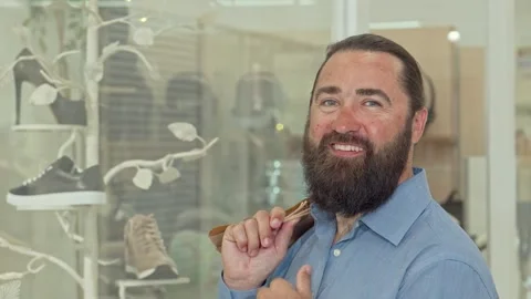 Joyful bearded man beaming at the camera while shopping in a stylish mall Stock Footage 311933570