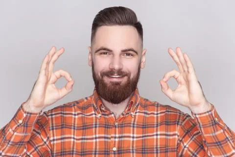 Joyful bearded man looking at camera, showing okay sign, ok gesture, expressing Stock Photos