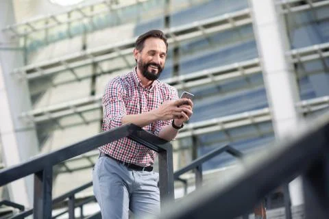 Joyful bearded man using his mobile phone outdoors Stock Photos