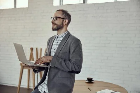 Joyful bearded man using notebook in cafe Stock Photos