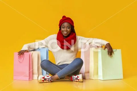 Joyful black girl sitting on floor among purchases Stock-Fotos