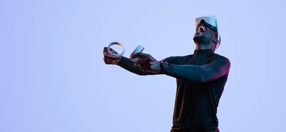 Joyful black guy shouting while playing video game in VR goggles Stock Photos