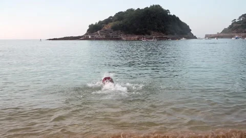 Joyful black man running into the ocean and swimming on vacation Stock Footage 338395526