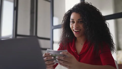 Joyful Black woman developer counting money, happy with startup earnings 스톡 동영상 332803602
