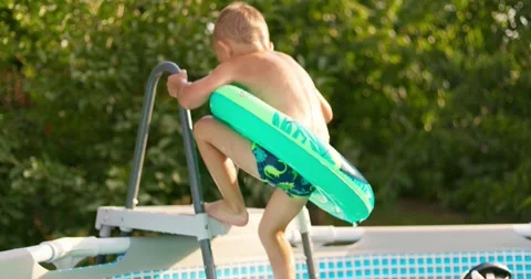 Joyful boy jumping into the pool in the backyard enjoying his summer vacation Stock Footage 254593185