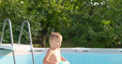 Joyful boy jumping into the pool in the backyard enjoying his summer vacation Stock Footage 254979061