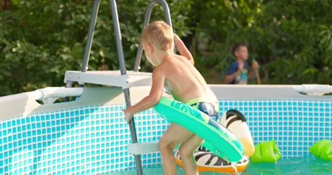 Joyful boy jumping into the pool in the backyard enjoying his summer vacation Stock Footage 255152528