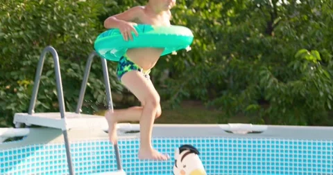 Joyful boy jumping into the pool in the backyard enjoying his summer vacation Stock Footage 255453358