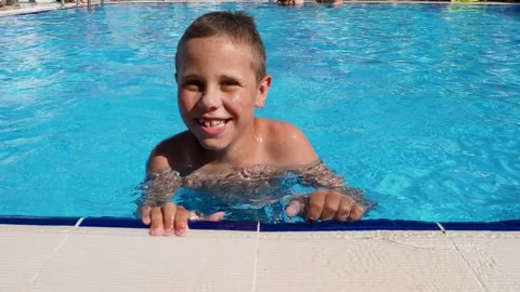 A joyful boy swims in the pool, swims up to the side and smiles. Stock Footage 307743338