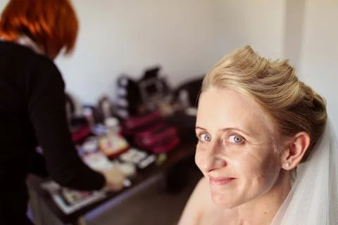 Joyful bride getting professional make up before wedding Stock Photos
