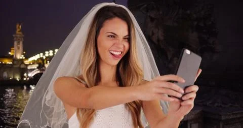 Joyful bride taking fun selfies in Paris at night Stock Photos