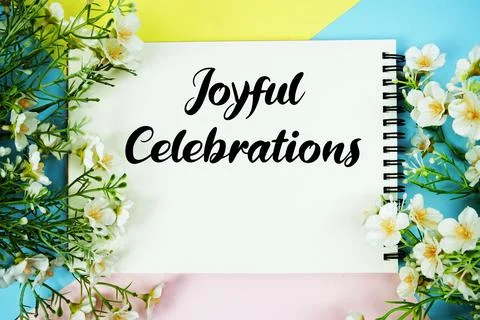 Joyful Celebrations text written on notepad with flowers decorations flat l.. Stock Photos