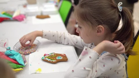 A joyful child decorates a gingerbread cookie during a colorful Stock Footage 280410187