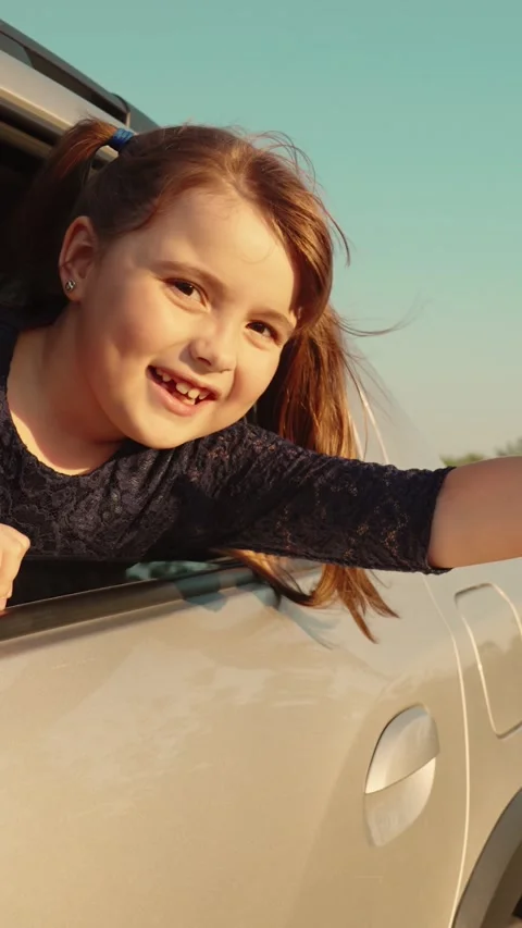 Joyful child extends hand out car window, her hair fluttering wind, capturing Stock Footage 281460136