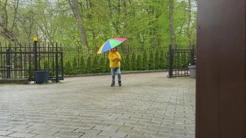 A joyful child is happily playing outdoors with a colorful umbrella during Stock-Footage 314711341