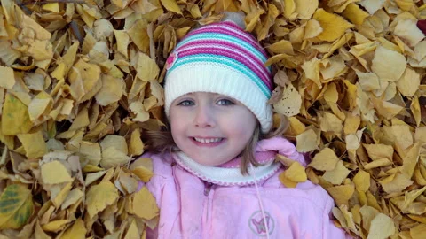 Joyful child lying half in fallen leaves Stock Footage 141468265