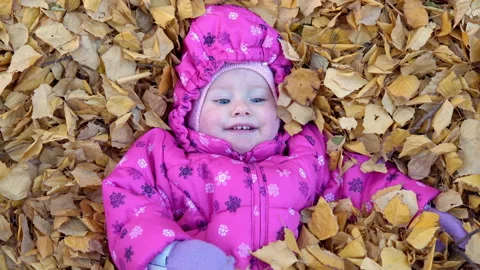 Joyful child lying half in fallen leaves Stock Footage 141468717